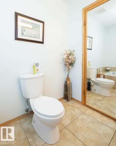 Ceramic tile flooring, full-length mirror with wood trim, and a built-in commode - 11007 108 Avenue, Westlock, AB 