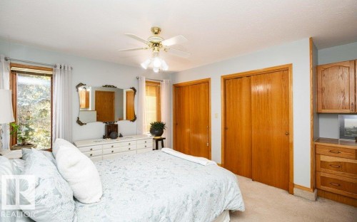 Multiple window openings, wood-finish doors, built-in wood-finish cabinetry, and a ceiling fan - 11007 108 Avenue, Westlock, AB 