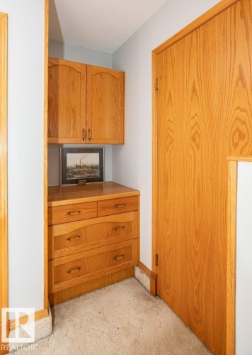 Built-in wood-finish cabinetry, wood-finish drawers, wood-finish door, and carpeted flooring - 11007 108 Avenue, Westlock, AB 
