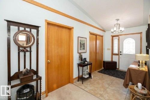 Front entryway featuring tiled flooring, a decorative front door with arched glass, and a modern chandelier - 11007 108 Avenue, Westlock, AB 