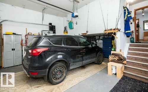 Attached garage space featuring concrete flooring, an overhead garage door system, and interior steps with carpeted treads - 11007 108 Avenue, Westlock, AB 