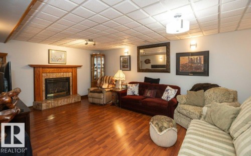 Wood-finish flooring, recessed tile ceiling, and a fireplace with a wood mantle and tile surround - 11007 108 Avenue, Westlock, AB 