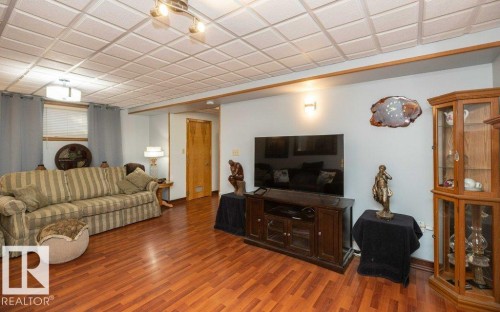 Wood-finish flooring, recessed ceiling with square tiles, wood trim, and a built-in display cabinet - 11007 108 Avenue, Westlock, AB 