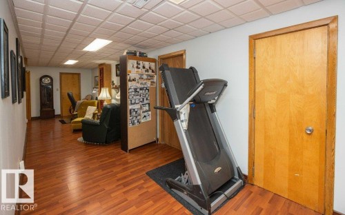 Wood-finish flooring throughout, white walls, and a drop ceiling with integrated lighting - 11007 108 Avenue, Westlock, AB 