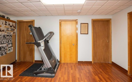 Wood-finish flooring with baseboard trim, drop ceiling with recessed lighting, and solid wood doors - 11007 108 Avenue, Westlock, AB 