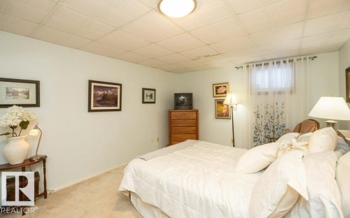 Recessed panel ceiling, light-toned wall paint, carpeted flooring, and a single window with blinds - 11007 108 Avenue, Westlock, AB 