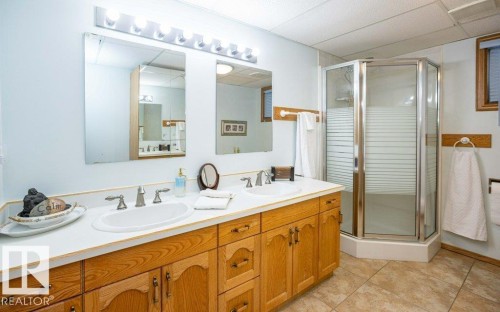 Dual vanity with white countertop, chrome fixtures, and wood-finish cabinetry - 11007 108 Avenue, Westlock, AB 