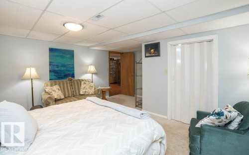 Recessed ceiling with acoustic tiles, flush-mount ceiling light, light-toned wall paint, neutral-toned carpet flooring, and a bifold closet door - 11007 108 Avenue, Westlock, AB 