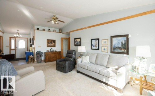 Vaulted ceiling with wood trim accents, a ceiling fan with light fixture, recessed lighting, and a white paneled front entry door with an arched window - 11007 108 Avenue, Westlock, AB 