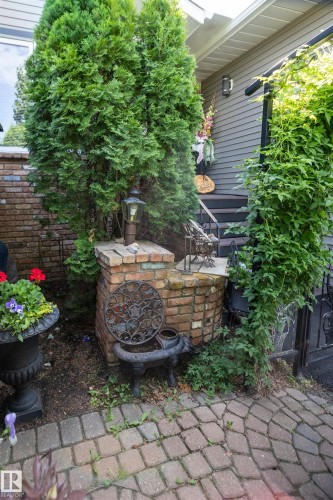 Brick paver walkway, brick retaining wall, mature evergreen plantings, exterior wall sconce, and dark siding - 11007 108 Avenue, Westlock, AB 
