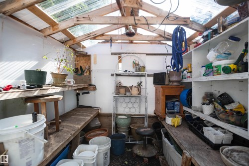 Greenhouse with translucent roof panels, exposed wood beam construction, built-in wooden workbenches, and integrated shelving units - 11007 108 Avenue, Westlock, AB 
