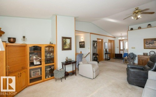 Vaulted ceilings, a built-in wood-finish display cabinet, and light-toned carpeting define this expansive room - 11007 108 Avenue, Westlock, AB 