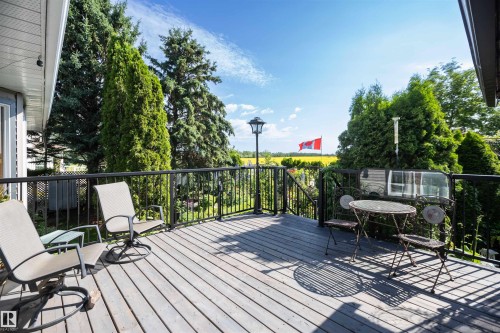 Expansive outdoor deck with wood-finish flooring, black metal railing, and a built-in lamp post - 11007 108 Avenue, Westlock, AB 