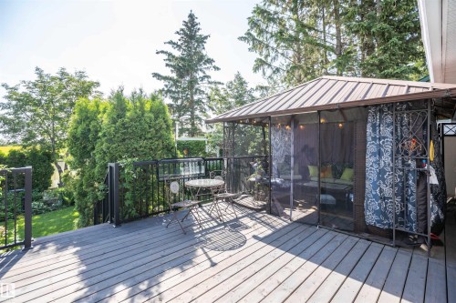 Expansive outdoor deck featuring wood-finish flooring, black metal railings, and a screened gazebo with a metal roof - 11007 108 Avenue, Westlock, AB 