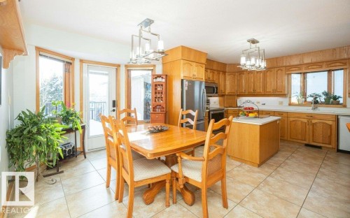 Kitchen featuring wood cabinetry, stainless steel appliances, a kitchen island, and tiled flooring - 11007 108 Avenue, Westlock, AB 