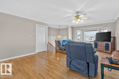 Hardwood-finish flooring, bay window, ceiling fan with integrated lighting, white trim, and a built-in storage unit - 14527 32 Street Nw, Edmonton, AB 