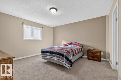Spacious bedroom with neutral wall finishes, carpeted flooring, and abundant natural light from a large double-hung window - 14527 32 Street Nw, Edmonton, AB 