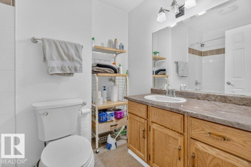 Vanity with integrated sink, wood-finish cabinetry, and a textured countertop - 14527 32 Street Nw, Edmonton, AB 
