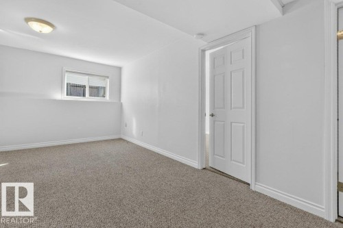 Light-colored wall-to-wall carpeting, white painted walls, window with blinds, overhead flush mount lighting, and a six-panel interior door - 14527 32 Street Nw, Edmonton, AB 