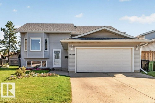 Light gray siding exterior with a dark shingle roof, featuring a bay window and a white garage door - 14527 32 Street Nw, Edmonton, AB 