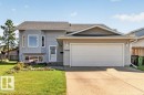 Light gray siding exterior with a dark shingle roof, featuring a bay window and a white garage door - 14527 32 Street Nw, Edmonton, AB 
