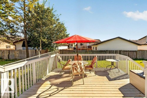 Spacious composite deck with white railings and wood-finish flooring, anchored by mature trees and bordered by residential fencing - 14527 32 Street Nw, Edmonton, AB 