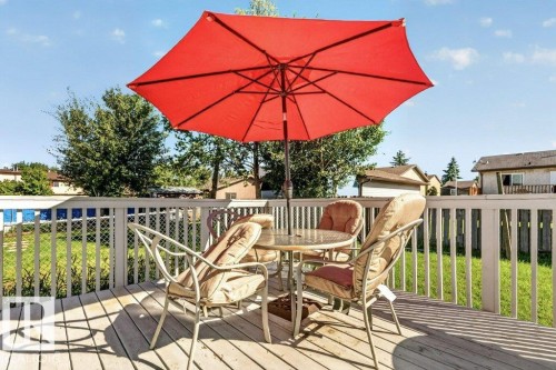 Expansive wood deck with white railing, overlooking a fenced backyard and mature trees - 14527 32 Street Nw, Edmonton, AB 