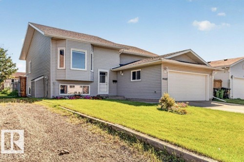 Split-level residence featuring light gray siding, a two-car garage, a bay window, and a front entry door with an adjacent sidelight - 14527 32 Street Nw, Edmonton, AB 