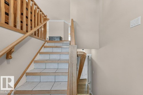 Staircase featuring wood railings and risers with tiled treads - 14527 32 Street Nw, Edmonton, AB 