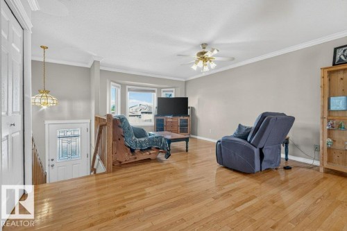 Hardwood flooring, bay window, ceiling fan, crown molding, and a decorative glass entry door - 14527 32 Street Nw, Edmonton, AB 