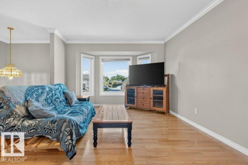 Hardwood flooring throughout, neutral paint, crown molding, and a bay window - 14527 32 Street Nw, Edmonton, AB 