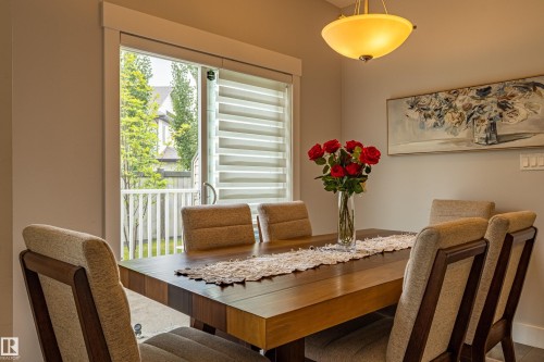 Dining area featuring a wood-finish table, sliding glass door with horizontal blinds, and a semi-flush mount ceiling light - #14 4835 Wright Dr Sw Sw, Edmonton, AB - Indoor Photo Showing Dining Room