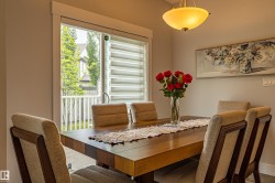 Dining area featuring a wood-finish table, sliding glass door with horizontal blinds, and a semi-flush mount ceiling light - 