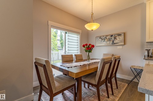 Dining area featuring a wood-finish table, upholstered chairs, and a contemporary pendant light fixture - #14 4835 Wright Dr Sw Sw, Edmonton, AB - Indoor Photo Showing Dining Room