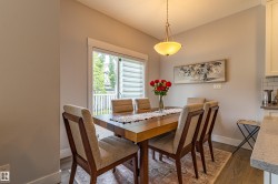 Dining area featuring a wood-finish table, upholstered chairs, and a contemporary pendant light fixture - 