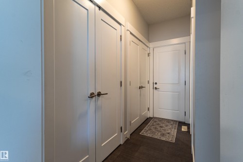 Hallway with wood-finish flooring, white panel doors, modern door hardware, and a recessed overhead light fixture - #14 4835 Wright Dr Sw Sw, Edmonton, AB - Indoor Photo Showing Other Room
