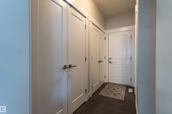 Hallway with wood-finish flooring, white panel doors, modern door hardware, and a recessed overhead light fixture - 
