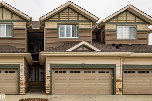 Multi-level townhome exterior featuring an attached garage, complementary siding, stone accents, and a shingled roof - #14 4835 Wright Dr Sw Sw, Edmonton, AB - Outdoor With Facade