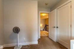 Carpeted hallway featuring a built-in closet with double panel doors and brushed nickel hardware - 