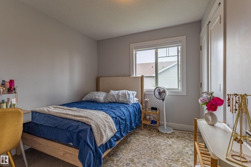 Bright bedroom space featuring a large window, light gray wall paint, and a textured area rug over carpet - #14 4835 Wright Dr Sw Sw, Edmonton, AB - Indoor Photo Showing Bedroom