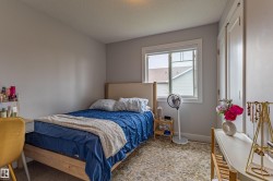 Bright bedroom space featuring a large window, light gray wall paint, and a textured area rug over carpet - 