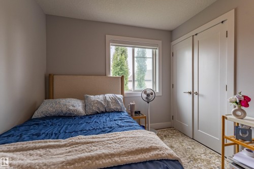 Bedroom featuring light gray walls, white trim, a double window, and a pair of white bifold closet doors - #14 4835 Wright Dr Sw Sw, Edmonton, AB - Indoor Photo Showing Bedroom