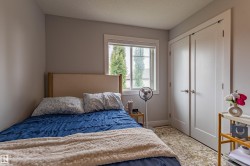 Bedroom featuring light gray walls, white trim, a double window, and a pair of white bifold closet doors - 