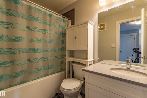 Bathroom featuring a built-in white vanity with an undermount sink, a light-toned countertop, and a wall-mounted mirror - #14 4835 Wright Dr Sw Sw, Edmonton, AB - Indoor Photo Showing Bathroom