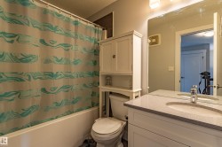 Bathroom featuring a built-in white vanity with an undermount sink, a light-toned countertop, and a wall-mounted mirror - 