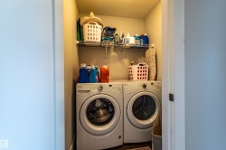 Dedicated laundry area featuring a front-loading washer and dryer, an overhead wire shelving unit, and textured ceiling finish - 