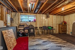 Unfinished basement with exposed wood joists and insulation-wrapped walls - 