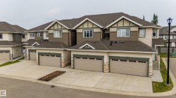 Contemporary townhome with attached garages, light-toned siding, and dark trim accents - 