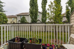 Private backyard featuring a wooden fence, green lawn, and mature trees - 