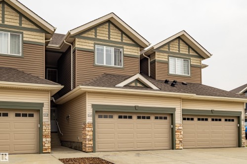 Contemporary multi-unit dwelling with integrated garages, two-tone siding, decorative stone accents, and peaked rooflines - #14 4835 Wright Dr Sw Sw, Edmonton, AB - Outdoor